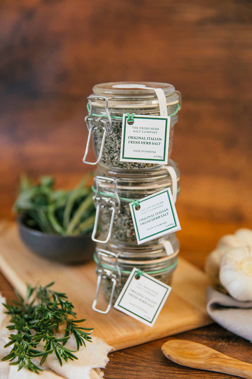 "Capture the essence of an Italian kitchen with this image showcasing 3 glass Kilner jars as a discounted package, filled with a vibrant Original Italian Fresh Herb Sea Salt Seasoning. The jar contains a harmonious blend of rosemary, garlic, basil, sage, and bay, set against a backdrop of white sea salt for a visually pleasing presentation. A convenient way to save money and give a jar to your friends as a gift!"