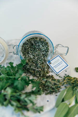 Discover the essence of Herbes de Provence in this image capturing a Kilner jar tipped on its side. The jar contains a flavourful blend of marjoram, sage, parsley, and thyme, expertly combined with coarse and fine pure white sea salt, creating a visually appealing and aromatic seasoning.